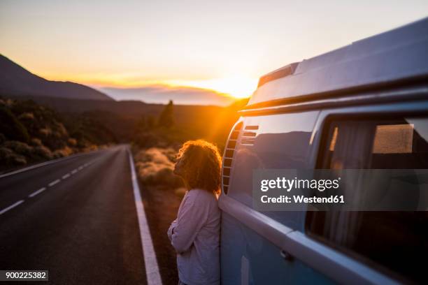 spain, tenerife, pensive woman at sunset leaning against van parked at roadside - straßenrand stock-fotos und bilder