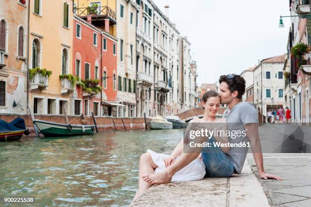 italy, venice, couple in love relaxing at canal - venice with couple stockfoto's en -beelden