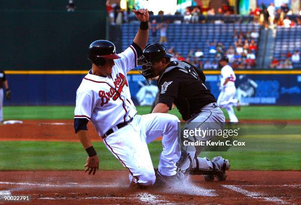 Kelly Johnson of the Atlanta Braves slides in safely past the tag of catcher John Baker of the Florida Marlins on August 22, 2009 at Turner Field in...