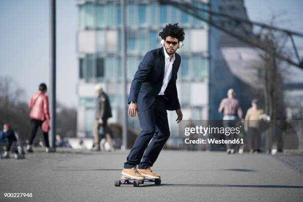 businessman riding longboard in front of skyscraper - black suit sunglasses stock pictures, royalty-free photos & images