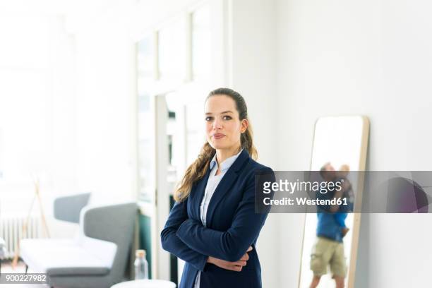 portrait of businesswoman with man and baby reflected in a mirror - geschäftskleidung stock-fotos und bilder