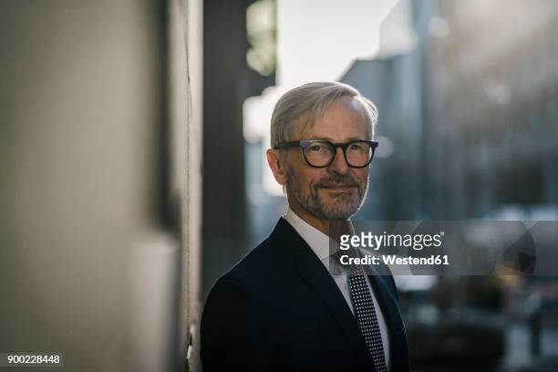 portrait of grey-haired businessman in the city - tiefenschärfe stock-fotos und bilder