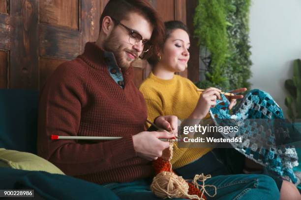 young couple knitting and crocheting in living room - crochet 個照片及圖片檔