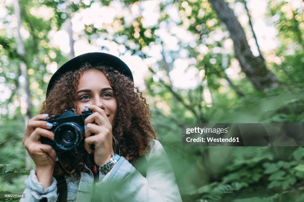 Portrait of smiling teenage girl taking pictures in nature