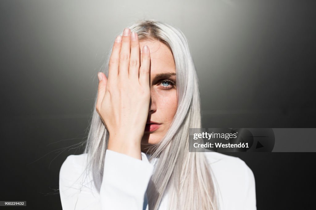 Portrait of serious young woman covering one eye