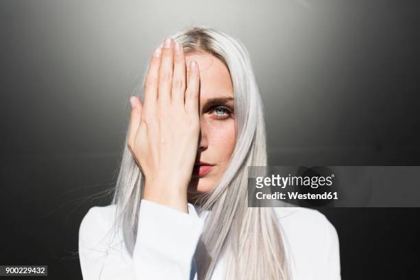 portrait of serious young woman covering one eye - woman silver hair young ストックフォトと画像