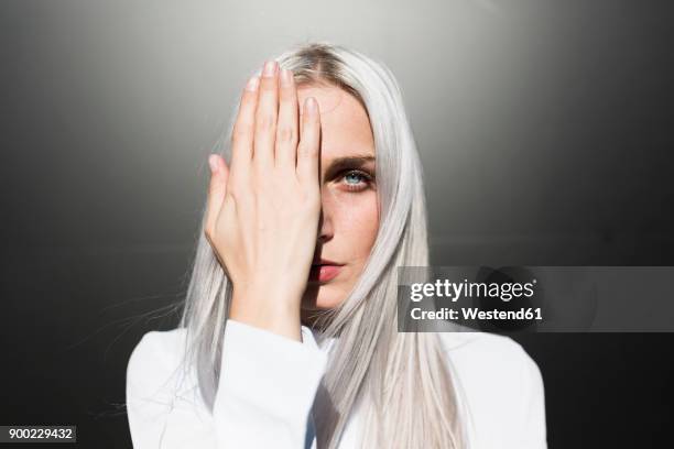 portrait of serious young woman covering one eye - special hair stock pictures, royalty-free photos & images