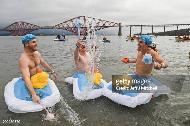Members of the public wearing fancy dress react to the water as they join around 1100 New Year swimmers, many in costume, in front of the Forth Rail...