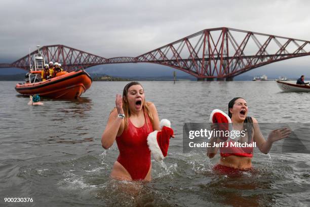 Members of the public wearing fancy dress react to the water as they join around 1100 New Year swimmers, many in costume, in front of the Forth Rail...