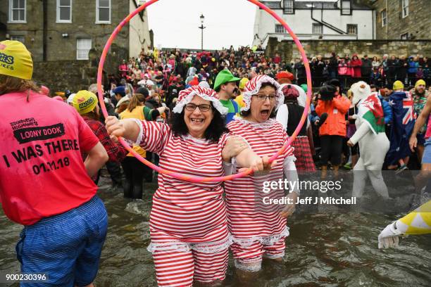 Members of the public wearing fancy dress react to the water as they join around 1100 New Year swimmers, many in costume, in front of the Forth Rail...