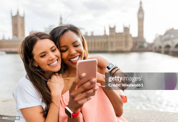 uk, london, two happy women with smartphone near westminster bridge - city of westminster london 個照片及圖片檔