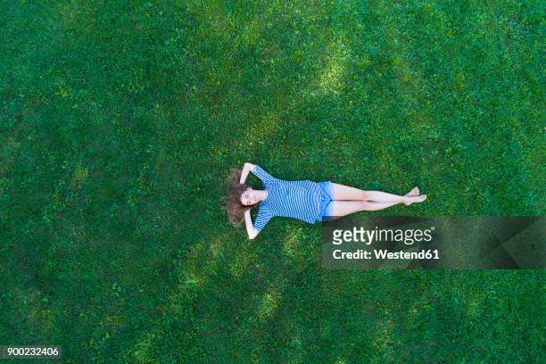 young woman lying on grass, daydreaming - vivere semplicemente foto e immagini stock