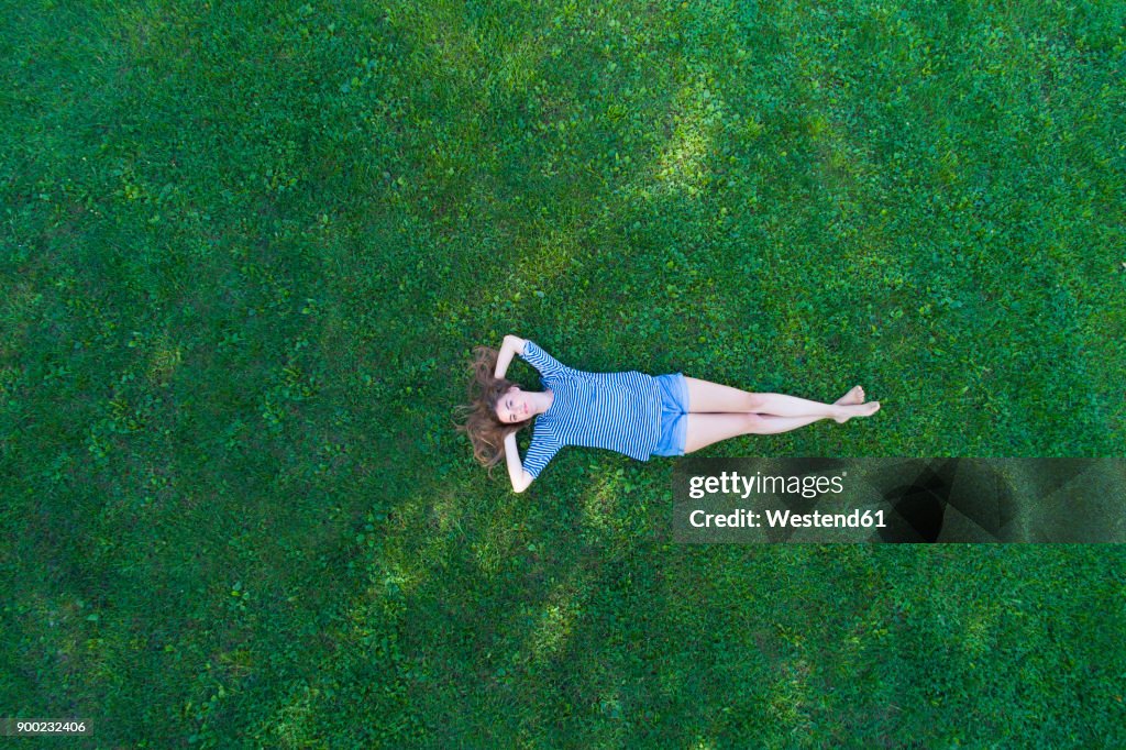 Young woman lying on grass, daydreaming