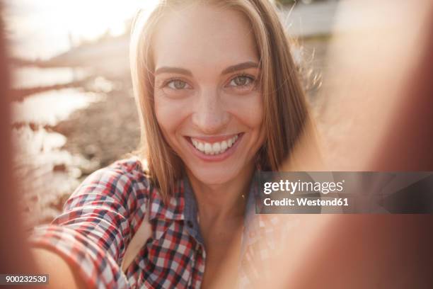 portait of happy young woman at the riverside - one finger selfie stock-fotos und bilder