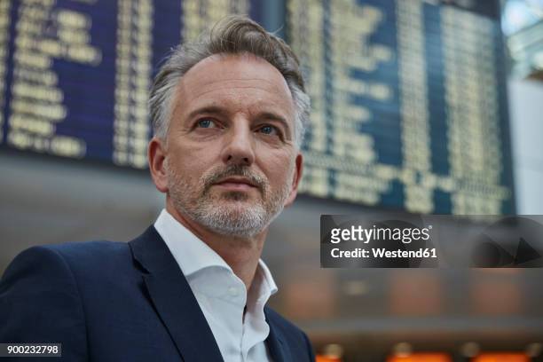 businessman at the airport in front of arrival and departure board - departure board front on stockfoto's en -beelden