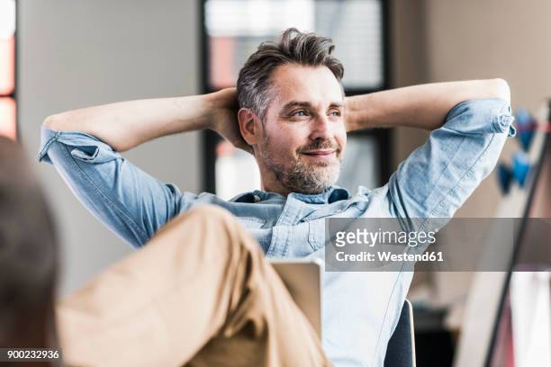 businessman in office leaning back - contento foto e immagini stock