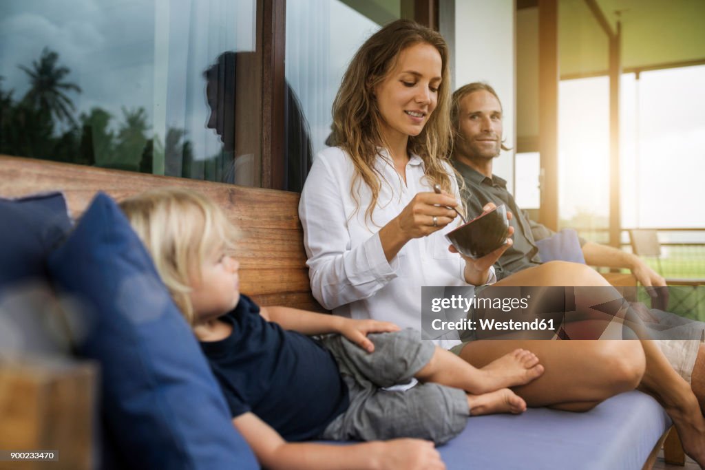 Family sitting on bench on balkony enjoying sunset together