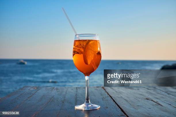 glass of ice-cooled spritz with orange slice in front of the sea - spritz drink stock pictures, royalty-free photos & images