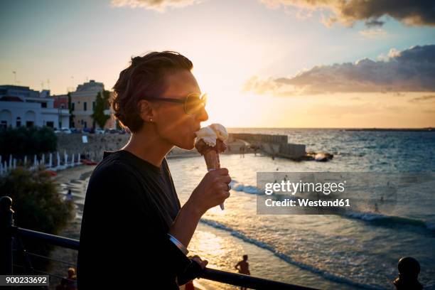 italy, santa maria al bagno, woman eating ice cream cone at backlight - mature women eating stock pictures, royalty-free photos & images