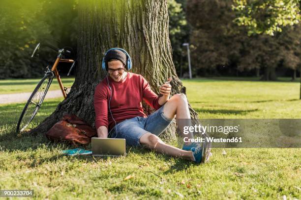 man using laptop in park - mann lässig gras sitzen stock-fotos und bilder