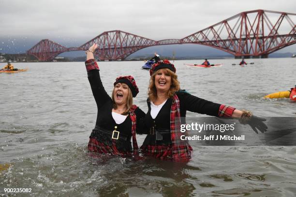 Members of the public react to the water as they join around 1100 New Year swimmers, many in costume, in front of the Forth Rail Bridge during the...