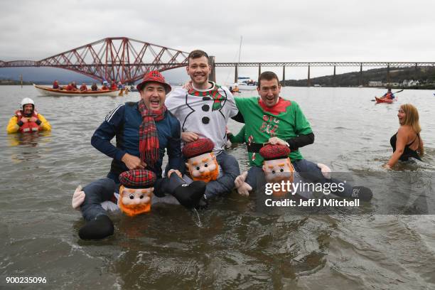 Members of the public wearing fancy dress react to the water as they join around 1100 New Year swimmers, many in costume, in front of the Forth Rail...