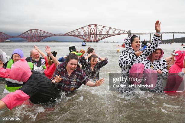 Members of the public wearing fancy dress react to the water as they join around 1100 New Year swimmers, many in costume, in front of the Forth Rail...