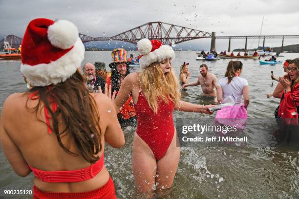 Members of the public react to the water as they join around 1100 New Year swimmers, many in costume, in front of the Forth Rail Bridge during the...