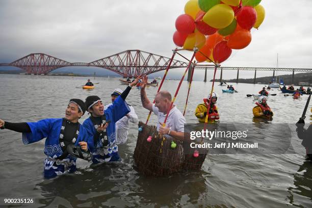 Members of the public react to the water as they join around 1100 New Year swimmers, many in costume, in front of the Forth Rail Bridge during the...