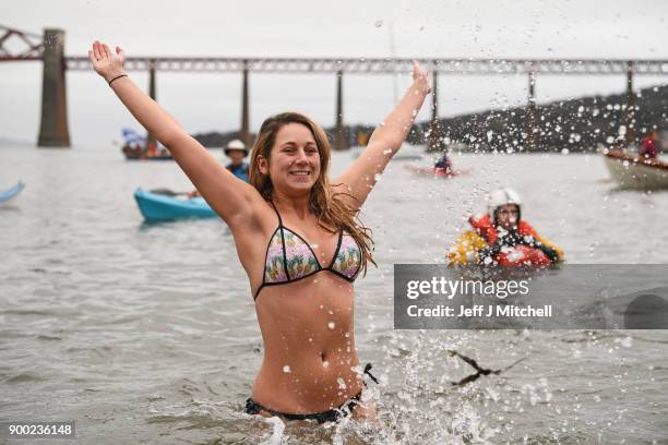 Members of the public react to the water as they join around 1100 New Year swimmers, many in costume, in front of the Forth Rail Bridge during the...