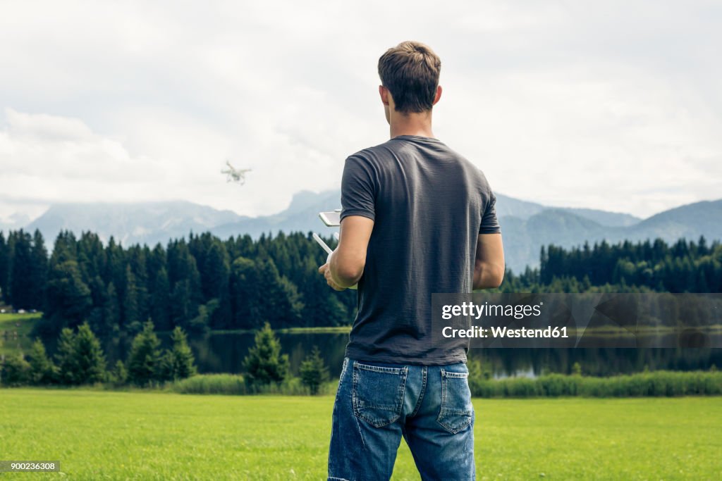 Germany, Bavaria, Pfronten, young man flying his drone at lakeside