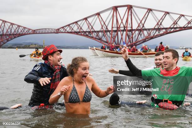 Members of the public react to the water as they join around 1100 New Year swimmers, many in costume, in front of the Forth Rail Bridge during the...