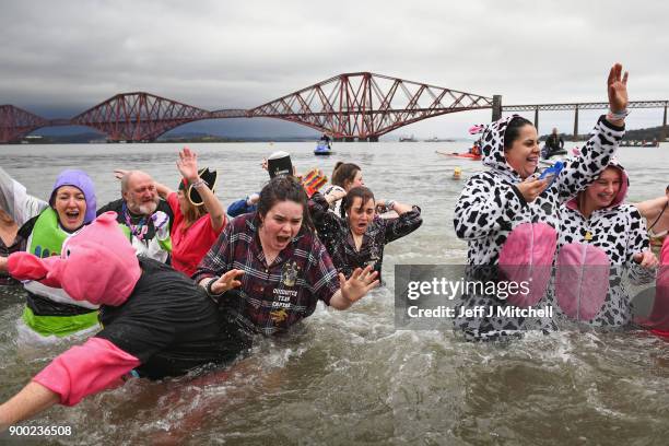 Members of the public react to the water as they join around 1100 New Year swimmers, many in costume, in front of the Forth Rail Bridge during the...