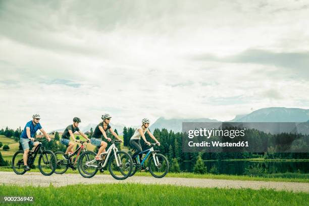 germany, bavaria, pfronten, family riding mountain bikes at ladeside - velofahren stock-fotos und bilder