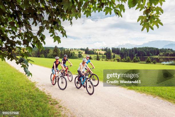 germany, bavaria, pfronten, family riding mountain bikes at ladeside - teenager cycling helmet stock pictures, royalty-free photos & images