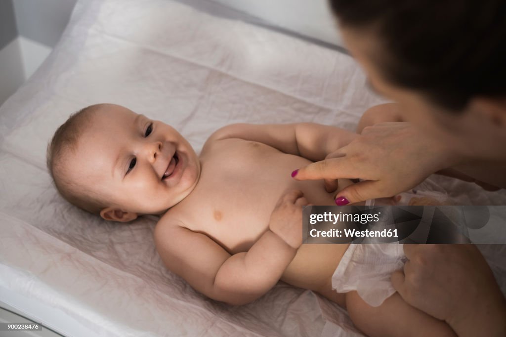 Mother changing diapers of baby girl
