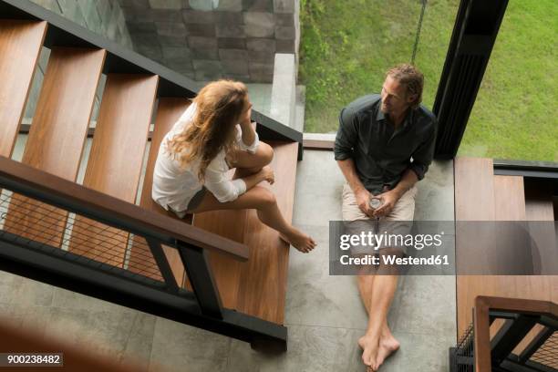 top view of couple having a talk on stairs in modern design house - build wealth stockfoto's en -beelden