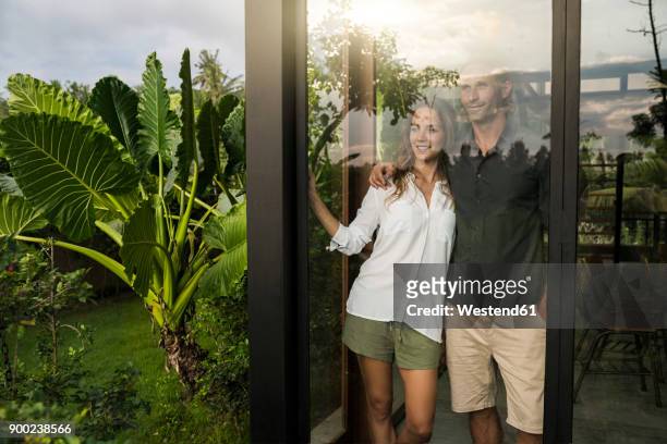 successful couple looking outside of window of modern design house - man front view stock pictures, royalty-free photos & images