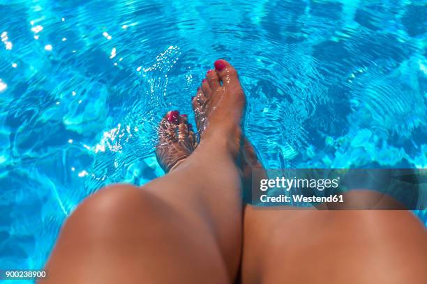 woman sitting at pool edge with legs in the water - zehennagel stock-fotos und bilder
