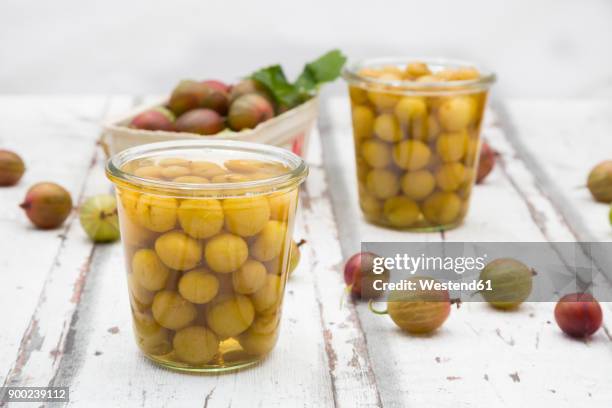 jar of preserved gooseberries and gooseberries on wood - stachelbeere stock-fotos und bilder