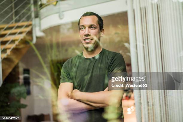 smiling man at home looking out of window - mid adult men stock pictures, royalty-free photos & images