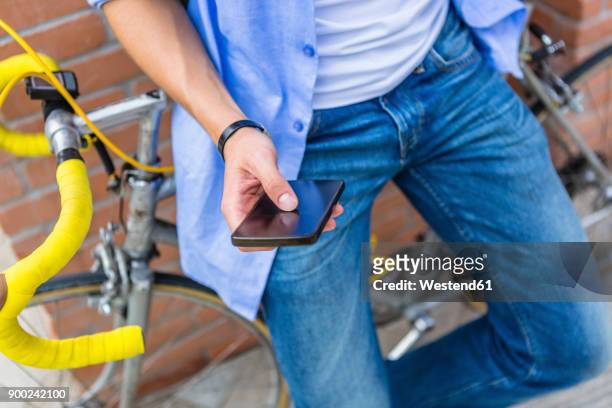 young man cell phone and racing cycle, partial view - standing with hands on knees imagens e fotografias de stock