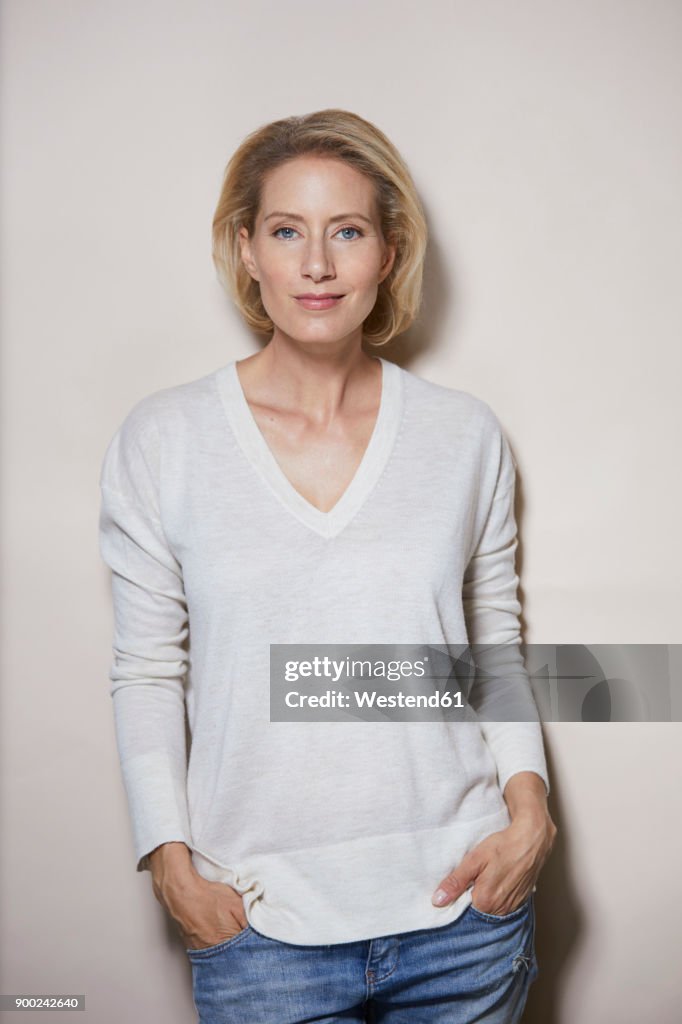 Portrait of smiling blond woman in front of light background
