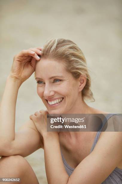 portrait of laughing blond woman sitting on the beach - beautiful woman beach stock pictures, royalty-free photos & images