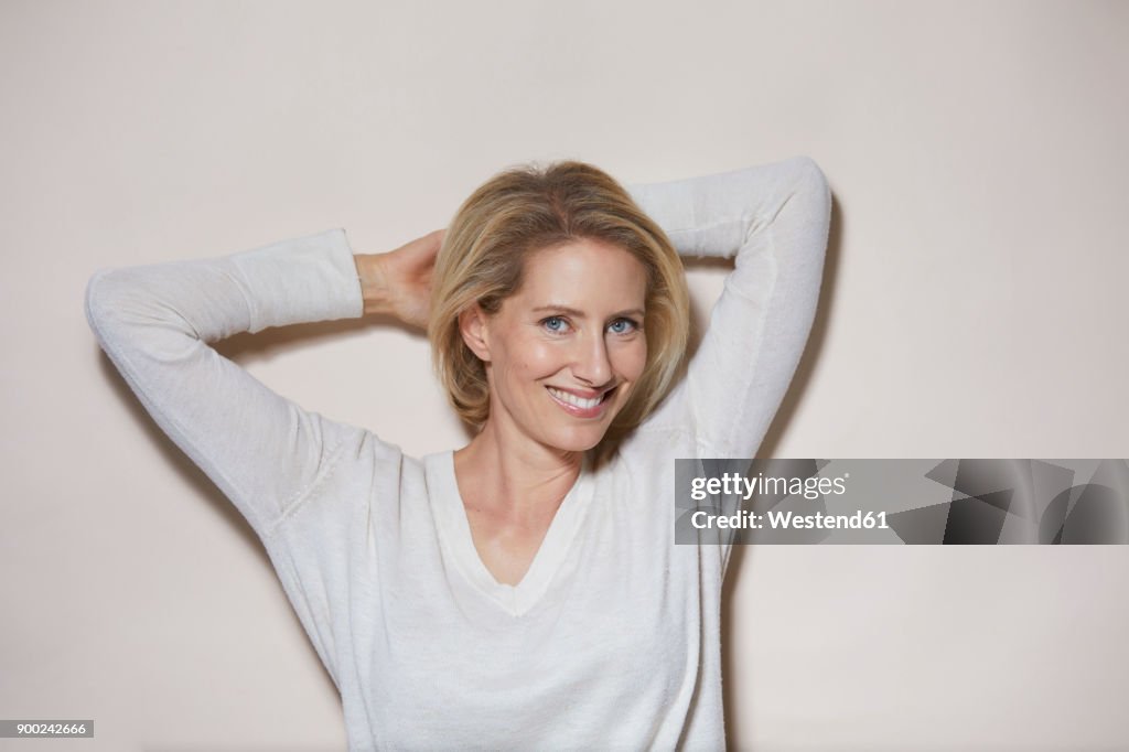 Portrait of smiling blond woman in front of light background