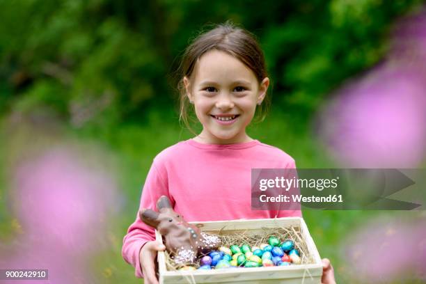 portrait of happy little girl holding easter nest - chocolate easter egg stock pictures, royalty-free photos & images