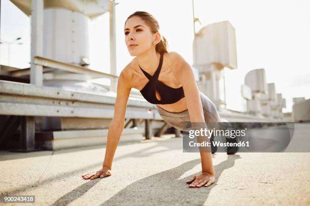young woman doing pushups in the city - flexiones fotografías e imágenes de stock