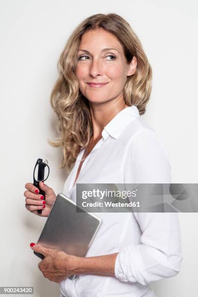 smiling businesswoman holding tablet and glasses - portrait white background looking away stockfoto's en -beelden