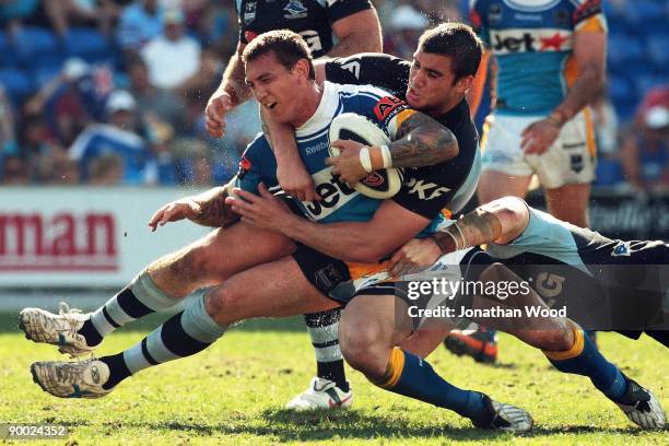 Mat Rogers of the Titans is tackled during the round 24 NRL match between the Gold Coast Titans and the Cronulla Sharks at Skilled Stadium on August...