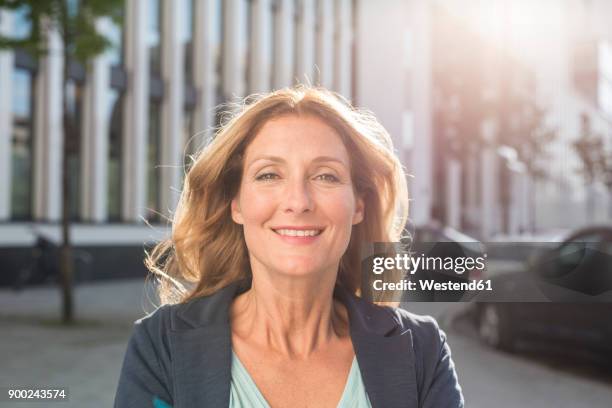 portrait of smiling woman in the city - tossing hair facing camera woman outdoors stock-fotos und bilder